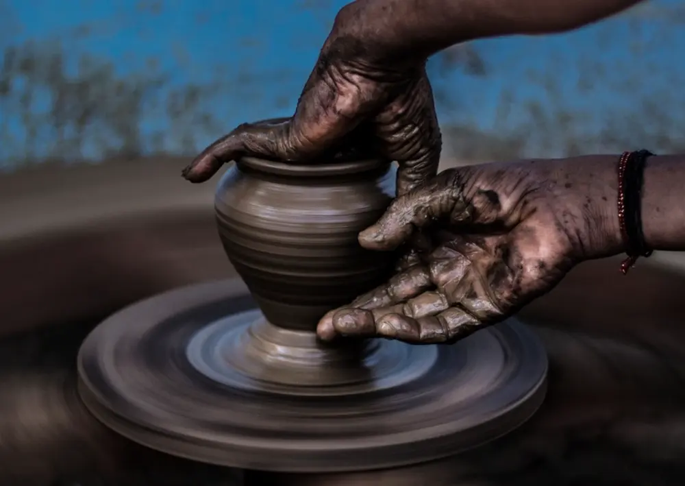 A potter shaping a pot on the wheel